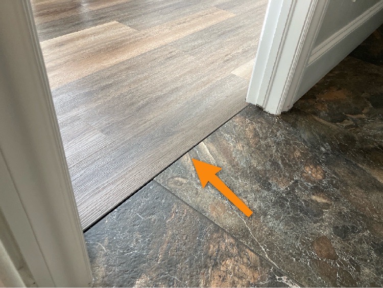 An arrow pointing to the lack of a transition piece between two rooms, leaving a one centimeter gap between the two