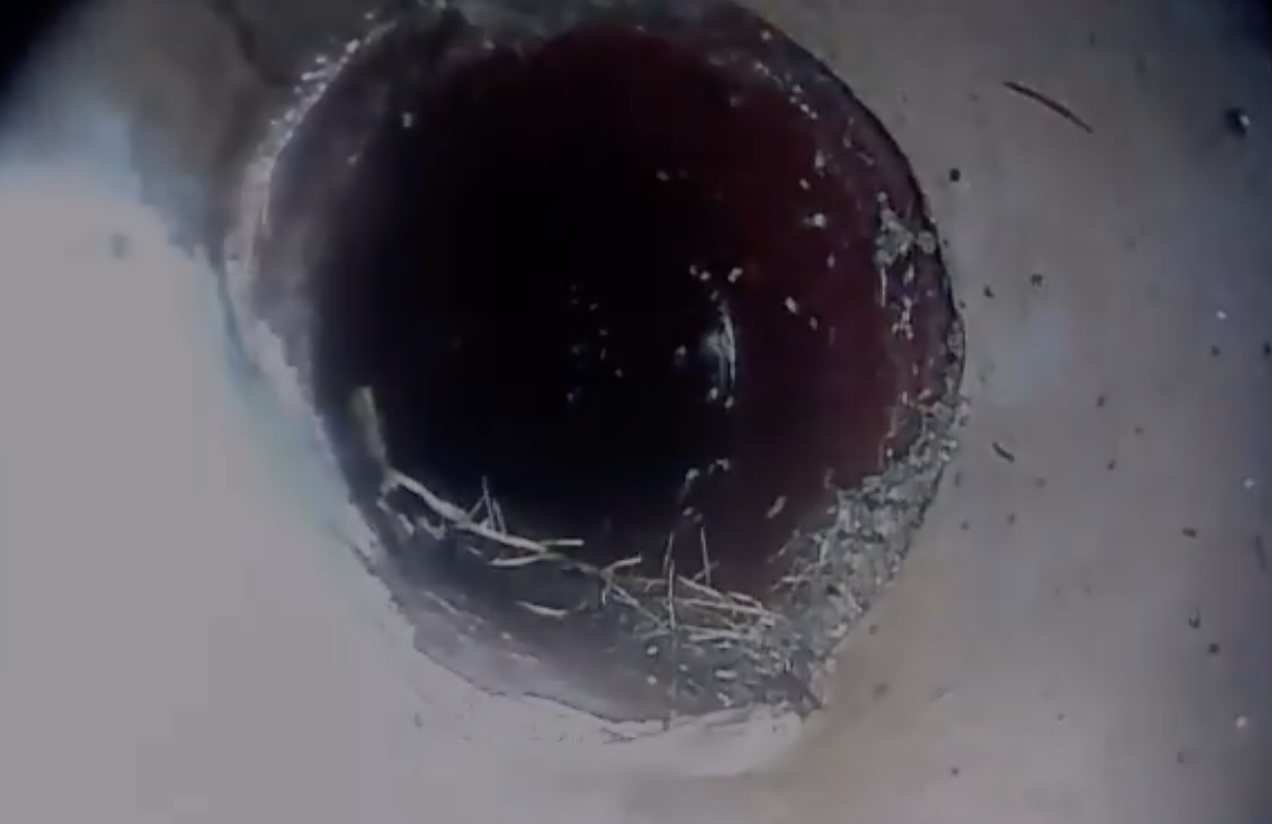 Debris accumulated at the bottom of an underground pipe, made visible during a sewer scope inspection
